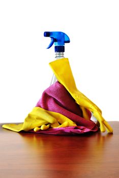 cleaning spray, yellow gloves and pink rag on table