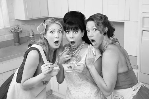 Three surprised middle-aged 1950s retro-style women with cigarettes and tea