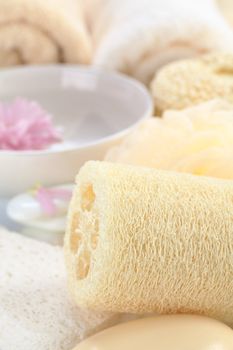 Spa still life with sponge, soap, flower and towels (Selective Focus, Focus on the left front part of the tube-like natural sponge)