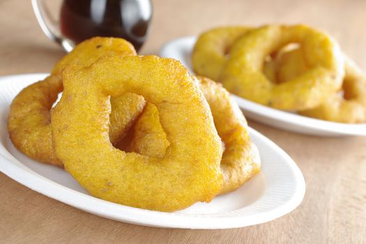 Popular Peruvian dessert called Picarones made from squash and sweet potato and served with Chancaca syrup (kind of honey), which can be seen in the back, on plastic plate (Selective Focus, Focus on the front)