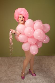 Big beautiful drag queen with pink balloons over green background