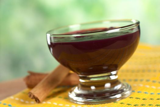 Popular Peruvian dessert called Mazamorra Morada (made out of purple corn) with cinnamon sticks on the side (Selective Focus, Focus on the front of the bowl)