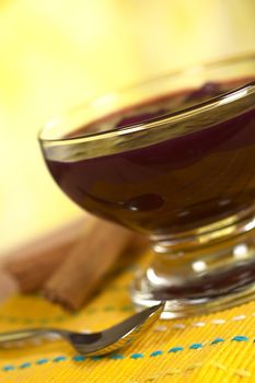 Popular Peruvian dessert called Mazamorra Morada (made out of purple corn) with cinnamon sticks and spoon on the side (Selective Focus, Focus on the front of the bowl)