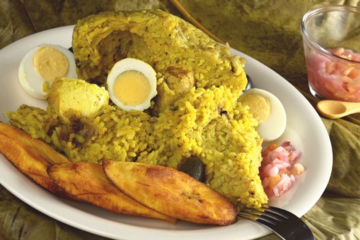 Traditional Peruvian food called Juane from the jungle area. This meal consists of rice, meat, eggs and black olives and is normally wrapped in bijao leaves which are spread below the plate. The meal is accompanied by fried plantains and a hot sauce out of onions, hot pepper and some fruits (Selective Focus, Focus on the rice)