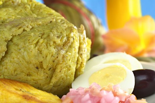 Traditional Peruvian food called Juane from the jungle area, in which rice, eggs and different kinds of meat are wrapped into bijao leaves, and are served with fried plantains, eggs and black olives (Selective Focus, Focus on the front of the rice)