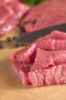 Fresh raw beef meat with knife and black pepper corns in the back (Selective Focus, Focus on the front of the beef)