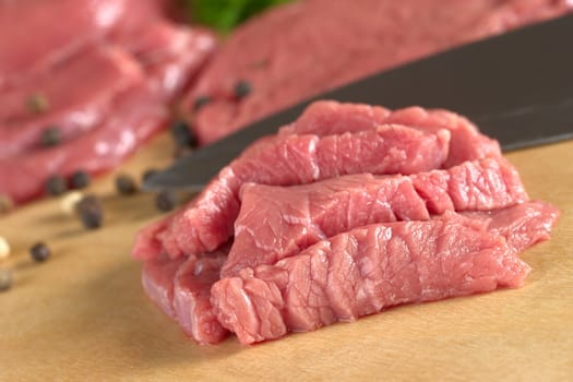 Fresh raw beef meat with knife and pepper corns in the back (Selective Focus, Focus on the front of the beef)