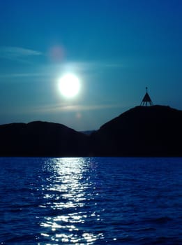 Sunset at the rocky coastline of Norway with a signal on one of the islands