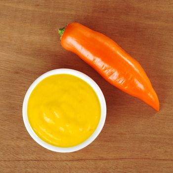 Hot salsa made of the Peruvian orange-colored hot pepper called aji on wooden board photographed from above 