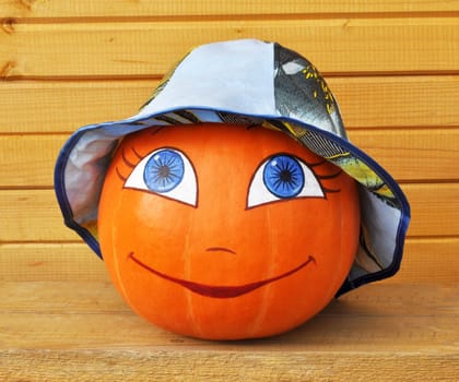 Pumpkin with female face in a colour children's hat, against wooden boards, photo by a Halloween
