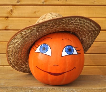 Pumpkin with female face in a straw hat against wooden boards, photo by a Halloween