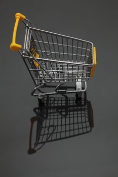 Image of an empty shopping cart and its shadows against a black background.