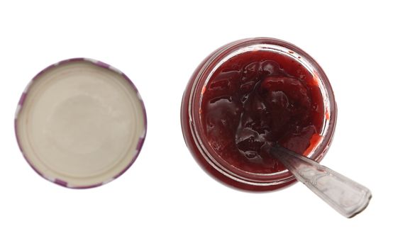 Upper view of a jar of strawberry jam with spoon in it, isolated against a white background. 