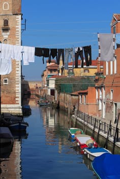 Specific canal with parked boats,specific architecture and clothes hanging out to dry in Venice,Italy.