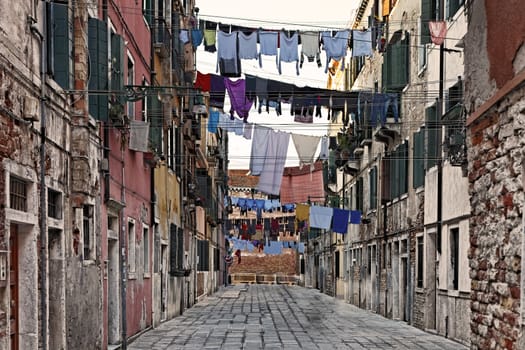 Traditional Italian street with clothes hanging out to dry between old houses, somewhere in Venice.