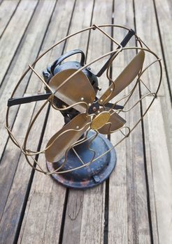 old antiquated electric fan on seasoned and soiled wooden decking