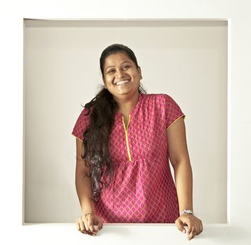 young Indian lady smiling at an open window clutter free background