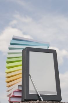 Stack of colorful books and electronic book reader