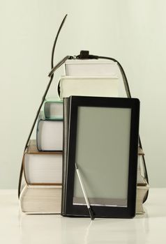 Stack of books and electronic book reader on the white background