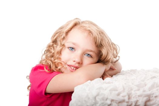 Beautiful cute happy smiling girl with blue eyes daydreaming laying on soft surface, isolated.