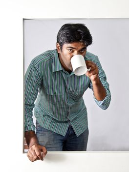 young man having a beverage at an open window