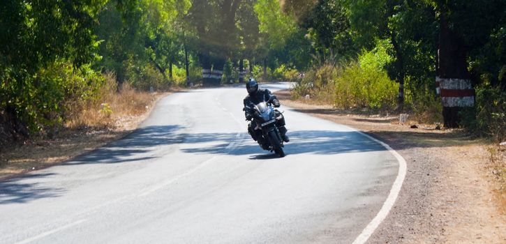 motorcyclist leaning and banking into a curve on mumbai goa road india