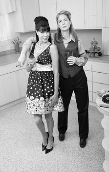 Lesbian couple with drinks and cigar in kitchen 