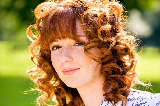 Close-up bright portrait of red-haired lovely young woman outdoors
