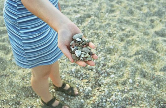 Women holding stones in hand. Standing on stoney beach.