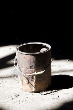 Still life shot of a rusty old paint bucket under dramatic lighting.