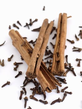 Cinnamon sticks on a spread of whole cloves. Studio isolated over white.