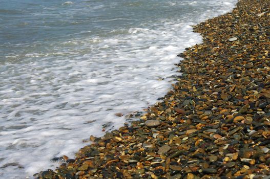 Sea-wave and shingle coastline on a bright day