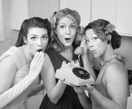 Three pretty women in kitchen with telephone