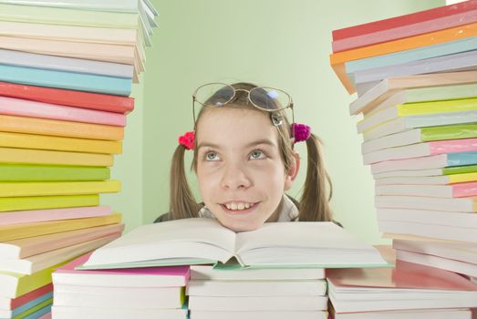 School girl sitting at the table with stacks of books
