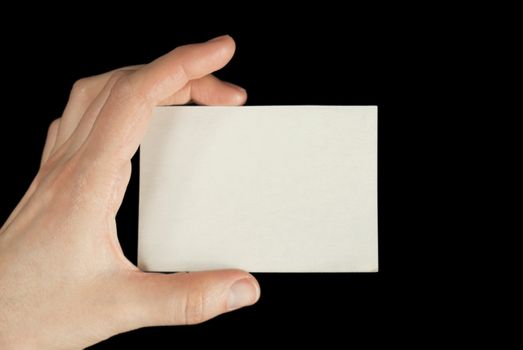 Hand holding a white card isolated on black background
