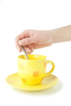 Yellow coffee cup with hand holding spoon isolated on the white background