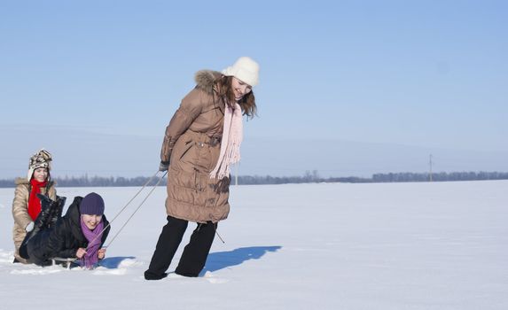 Three happy sisters sledding at winter time