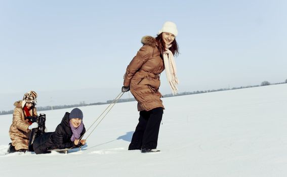 Three happy sisters sledding at winter time