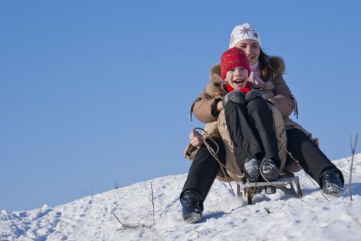 Two happy sisters sledding at winter time