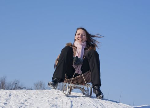 Teen girl sledding from a hill