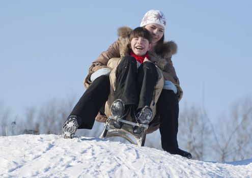 Two happy sisters sledding at winter time