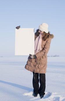 Girl holding white poster at winter snowy field