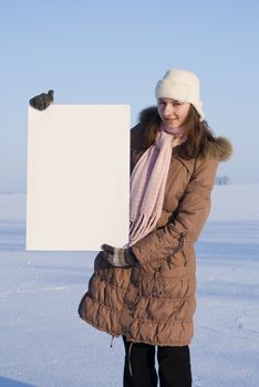 Girl holding white poster at winter snowy field