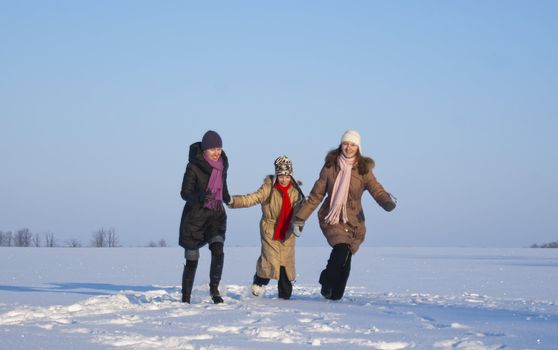 Three girls running on the snowy field