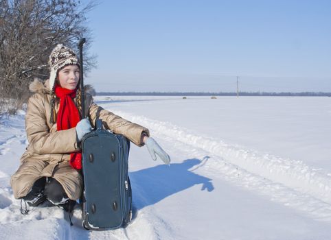 Teen girl with a suitcase outdoors at winter time