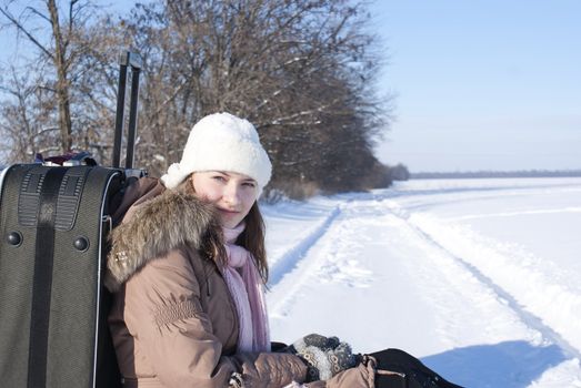 Teen girl with a suitcase outdoors at winter time