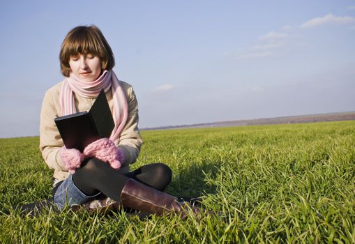 Young lady reading a book sitting at grass