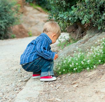 Cute 2 years old boy sitting on the footpath in the park