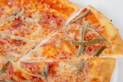 pizza closeup with boiled sausage, ham, marinated gherkin and mozzarella cheese