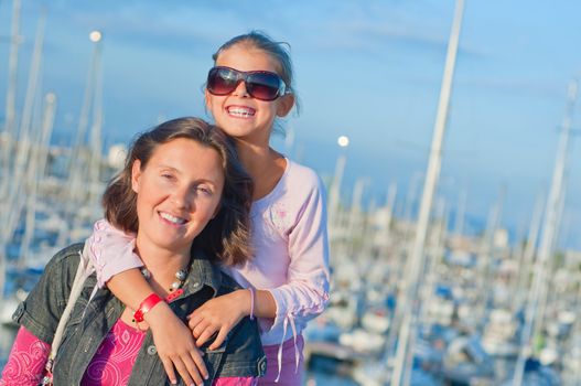 Closeup Portrait of a cute girl with her mother in the background of yachts